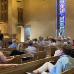 Zach Hemenway presenting to seated audience in church sanctuary during 'Getting to Know Epiphany: All About Evensong' talk