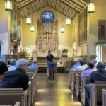 Parishioners and visitors seated in church pews listening to presentation about Evensong history and Anglican worship traditions